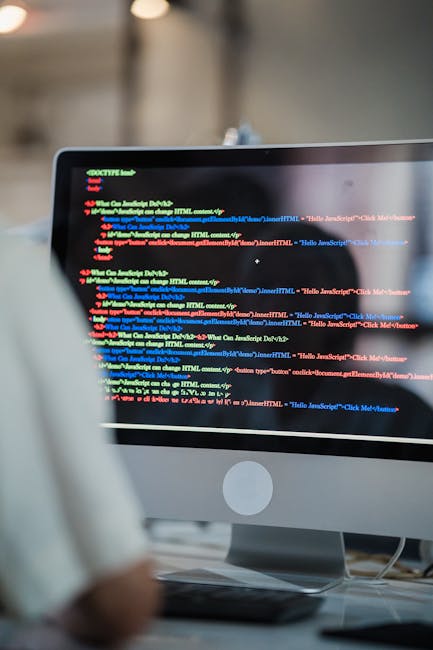 Close-up photograph of a computer screen displaying lines of colorful programming code on a dark background. The code is written in a text editor with syntax highlighting, featuring various colors suc